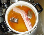 豚の角煮　豚バラ肉ブロックを紅茶で煮ている写真